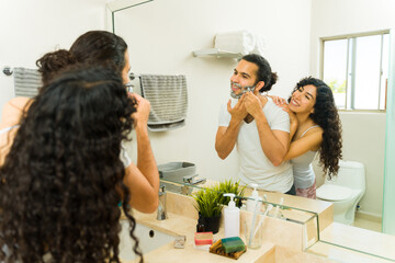 Happy couple in the bathroom using grooming products