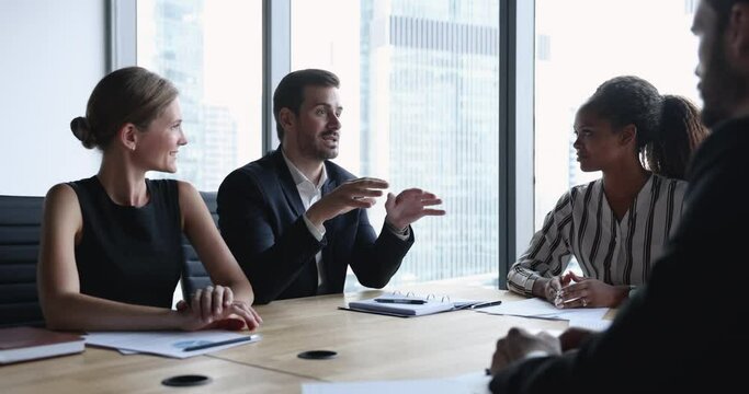 Company boss hold formal meeting with partners, investors or clients, make speech seated at desk with entrepreneurs share strategy, reporting, forecasting, brainstorming together in conference room