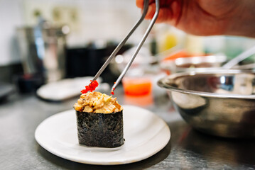 Chef's hands cooking gunkan sushi roll on kitchen
