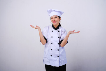 Photo of smiling female Asian chef standing with open palms, warm welcome gesture on empty space or...