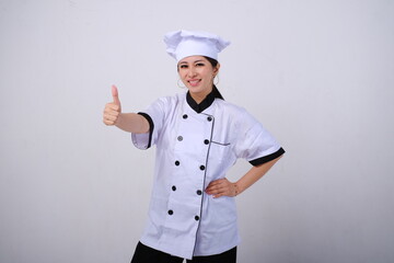 Photo of smiling female Asian chef standing showing thumb up like gesture of approval on isolated white background