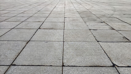 Gray tiles on the sidewalk in the city outdoors. Background and texture with lines and squares of tiles. Abstract frame, copy space, place for text