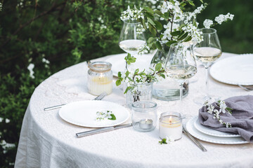 Rustic zero waste wedding decor with natural elements. Fresh spring blooming flowers, candles, linen napkins, wine glasses. Eco friendly decoration for the special holiday dinner. Romantic cozy place