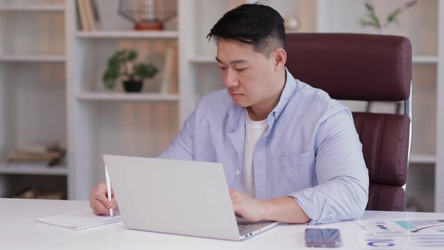 Focused man look ap pc screen writes ideas questions do review make research sit at desk. Businessman learn language improve knowledge, self-education, modern tech educational app concept
