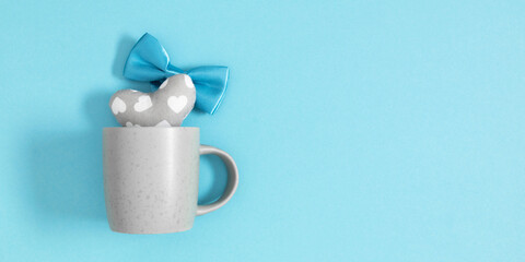 Minimal Father's Day concept. Flat lay top view of gray cup with blue bow tie and heart on blue isolated background with space for text or promotion and greeting message, banner