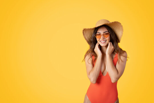 Smiling millennial asian woman in swimsuit, hat and sunglasses enjoys resort vacation, beach trip