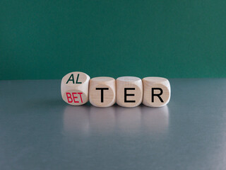 Alter or better symbol. Turned wooden cubes and changed the word Alter to Better. Beautiful grey table, green background, copy space. Business and alter or better concept.