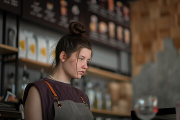 Portrait of a young beautiful barista girl in a coffee shop.