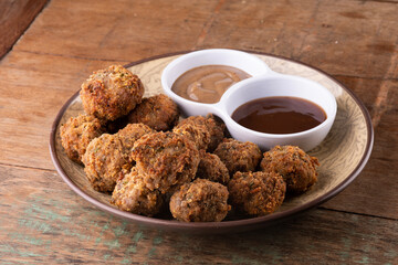 appetizer portion of pub tapas meatloaf dumpling or mini kafta kibis with black mustard and barbecue sauce on rustic wooden table close view