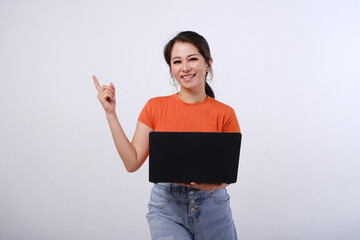 Photo of smiling female Asian hold laptop with hands pointing on empty space or copy space for product isolated on white background