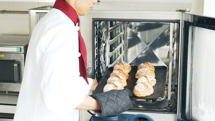Baker taking bread out of the oven.