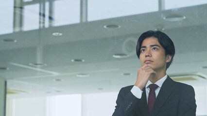 窓から外を見る若いビジネスマン