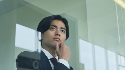 窓から外を見る若いビジネスマン