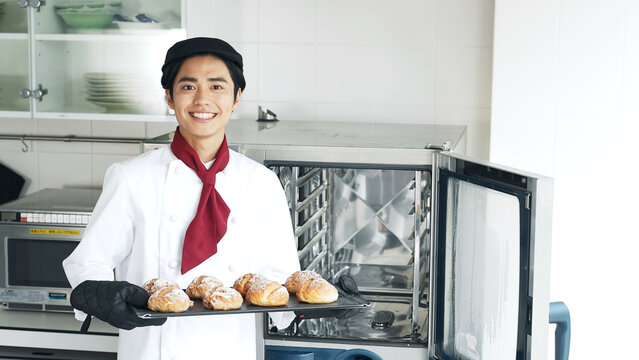 オーブンからパンを取り出すパン職人