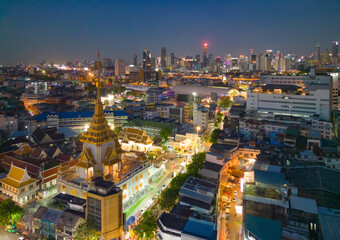 Fototapeta na wymiar Aerial top view of Wat Ratchanatdaram pagoda, a buddhist temple or Wat Saket in Bangkok Downtown, urban city with sunset sky, Thailand. Thai architecture landscape background.
