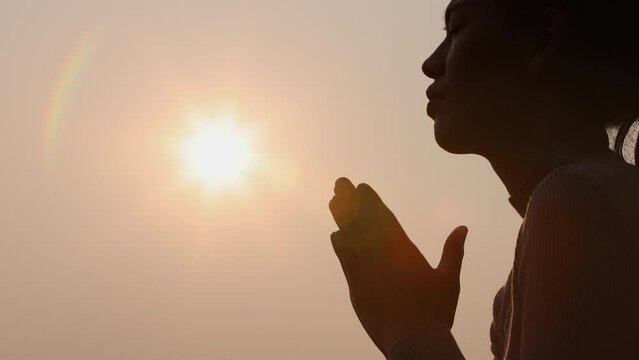 Silhouette of a woman raising her hands while the sun was rising. hope and faith Remember the Lord.
