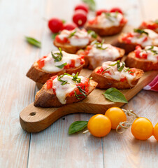 Toasts with cheese and tomato sprinkled with fresh basil, close up view