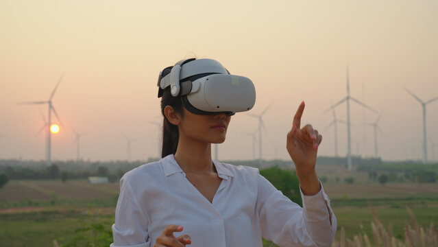 Female engineer wearing vr at wind turbine farm. She using vr to check data or Program at wind turbine farm.