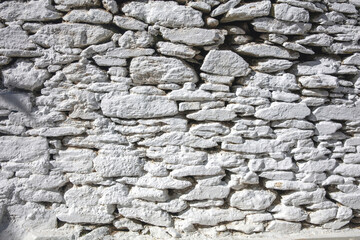 Rocky wall construction background texture. Old grey stonewall, blank masonry sunny day. Copy space.