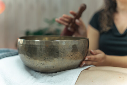 Sound massage, treatment with Tibetan bowls in the spa salon. Female meditation during traditional Nepalese practices using the vibration of bronze bowls for energy recovery