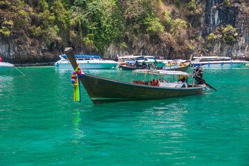 Naklejka na ściany i meble A picturesque beautiful place on the island of Phi Phi Leh - Pi Leh Lagoon is popular for excursions with tourists on traditional Thai fishing boats. Island travel in Thailand.