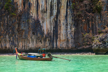 Naklejka na ściany i meble A picturesque beautiful place on the island of Phi Phi Leh - Pi Leh Lagoon is popular for excursions with tourists on traditional Thai fishing boats. Island travel in Thailand.