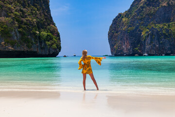 Beautiful young blonde woman in orange dress on a Maya Bay Beach during excursion of phi phi leh...