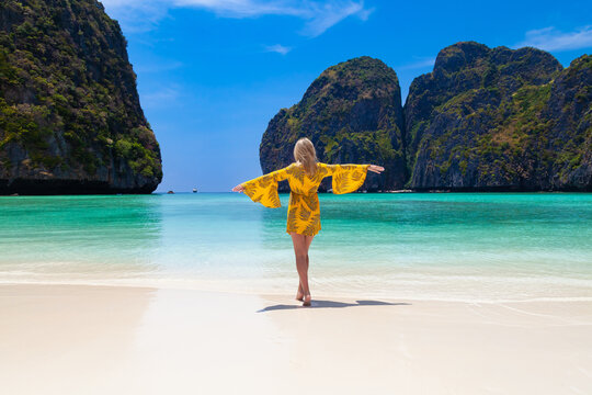 Beautiful young blonde woman in orange dress on a Maya Bay Beach during excursion of phi phi leh island in andaman sea thailand.