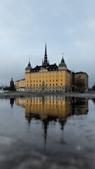 Fototapeta na wymiar Yellow caste and cloudy blue sky reflecting in water puddle on street Sweden Stockholm