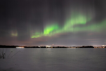 Enchanting Frozen Lake: Vibrant Green Aurora Illuminating the Night Sky