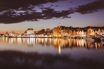 Captivating night view of Bergen's iconic Bryggen marina, adorned with shimmering reflections over the tranquil waters, showcasing the enchanting ambiance of the city's vibrant nightlife, illuminated 