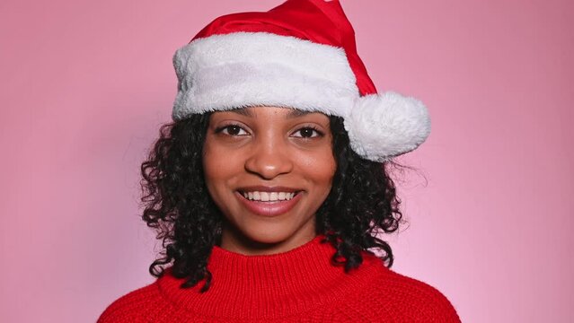 Closeup potrait of happy smiling girl in santa hat in studio on pink background