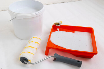 Paint can, roller and paint tray for painting wall on the floor