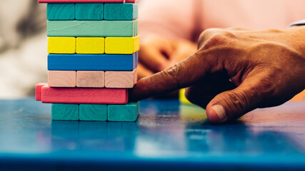 Senior people playing a wooden block tower, risk and strategy of project management. Concept of business risk with domino blocks. Older People playing jenga block removal game on table at home