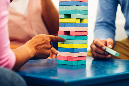 Senior people playing a wooden block tower, risk and strategy of project management. Concept of business risk with domino blocks. Older People playing jenga block removal game on table at home