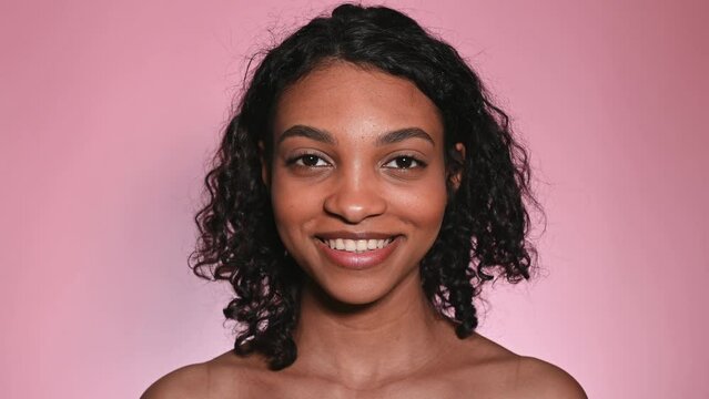 Studio footage of smiling african woman on pink background.Natural beauty.Skin care concept