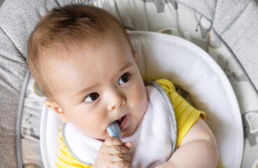 adorable cute baby boy sitting in swing cradle eating mashed food with spoon.mother hand feeding...