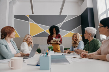 Group of happy mature women having business meeting while sitting at the desk together