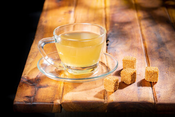 Cane panela tea in a glass cup, on a wooden surface, royalty free