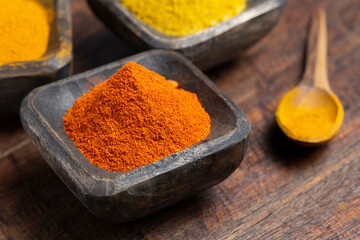 Turmeric, pepper and curry powder in container on wooden background