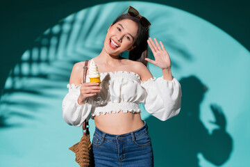 enjoy smiling attractive asia teen female woman wear casual t-shirt cloth happiness facial expression hand hold ice cream waffle cone summer lifestyle vacation travel studio shot on blue colour