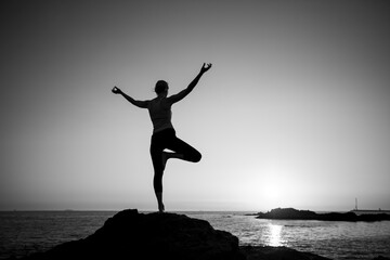 Fototapeta na wymiar Silhouette of a yoga woman on the ocean shore. Black and white photo.