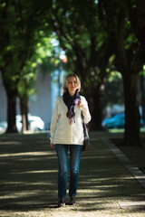 A woman walks down an alley in a green park.