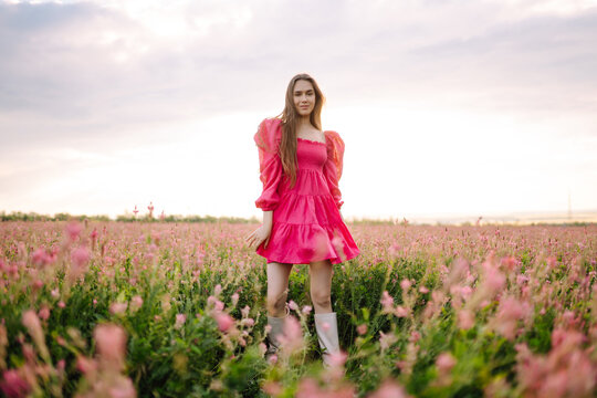 Young woman in stylish summer dress feeling free in the field with flowers. Nature, fashion, vacation and lifestyle