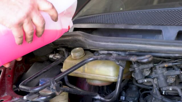Pouring coolant, Service of cars. Pouring antifreeze. Mechanic fills the coolant G12 to tank in the engine. Automobile maintenance, coolant exchange in old car.