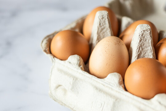 Open egg box with ten brown eggs. Brown hen eggs in carton box. Close up image of organic chicken eggs