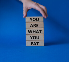 You are what you Eat symbol. Concept words You are what you Eat on wooden blocks. Beautiful blue background. Doctor hand. Healthy eating and You are what you Eat concept. Copy space.