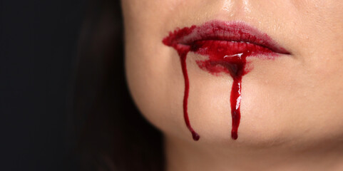 Close up of a woman's lips with blood dripping from her mouth - obrazy, fototapety, plakaty