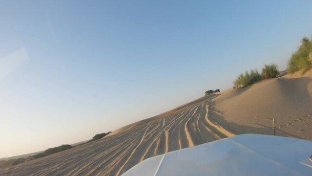 4K POV of a vehicle dune bashing on the sand dunes of the Thar desert at Jaisalmer in Rajasthan, India. Car moves on the desert during the day. Extreme adventure in the desert background.	