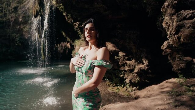 Beautiful model in a turquoise dress posing near a mountain waterfall.Wildlife concept